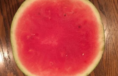A half of a seedless watermelon on a wood table.