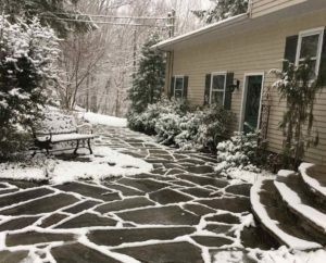 a bluestone patio and foundation planting in a disting of snow