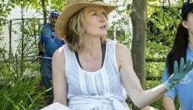 Mary Stone in a straw garden hat and white shirt and jeans talking with high school kids