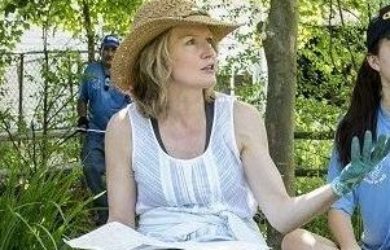 Mary Stone in a straw garden hat and white shirt and jeans talking with high school kids
