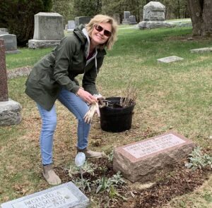 a woman tending to a garden around a gravestone