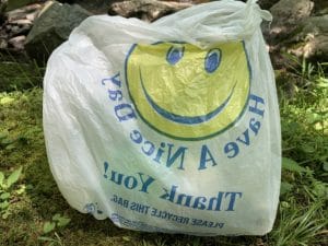 Bag of trash in a white bag wiht a smiley face that says have a nice day