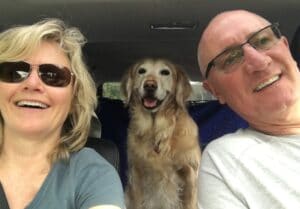 a selfie of a man and woman in a car with a golden retriever