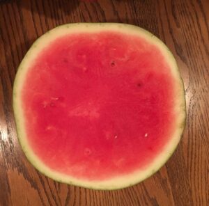 a half of an organic and non-gmo seedless watermelon on wood table