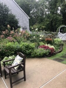 a cottage garden with patio and white picket fence