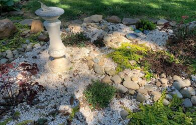 a sundial in a garden of gravel and river stone and sedum