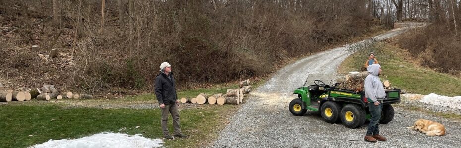 two men and a John Deer tractor loaded with EAB nfested logs