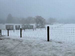 a foggy farm field with snow on March first.