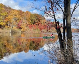 Canoers on Catfish Pond with a hillside of fall color reflecting in the water