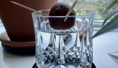 an avocado seed suspended with toothpicks on a crystal glass on a windowsill