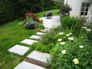 a step stone path of square stones leading to a stone patio