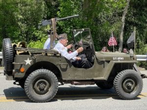 an elderly man in a historic US Army jeep waving an American Flag at the Blairstown Memorial Parade of Remembrance