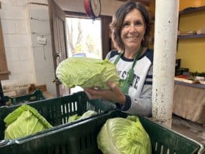 Lois, a middle-aged brunet holding a head of cabbage