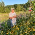 A man in a ballcap and t-shirt while sharing the story of the antics of meadow wildlife he witnessed.