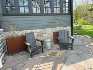a stone patio with dark grey chairs and steel planters