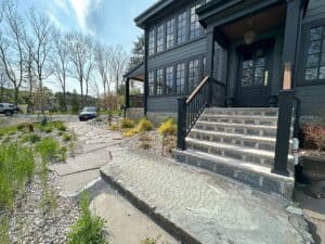A stone landing and patio in front of a grey 1800s farmhouse