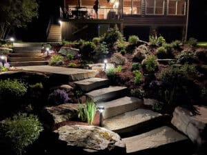 A stone staircase in the nighttime with subtle landscape lighting.