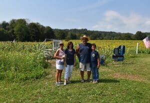Raj Sinha, owner of Liberty Farm (and his son) standing in his Sussex County Sunflower Maze with members of Mental Health Association.