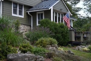 The front of a green house with an American Flag and an Alpine garden.