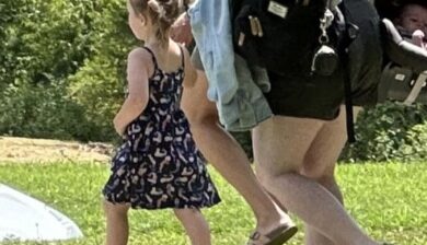 a little girl in a blue sundress and pigtails holding hands with her mom.