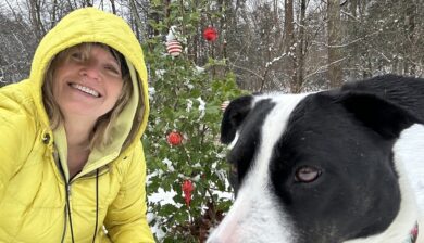 Mary Stone in a yellow jacket with Jolee in front of Ellie's memorial holly.