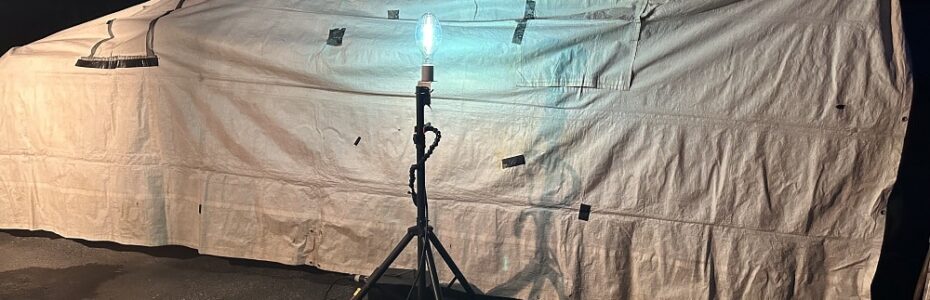 a twenty-foot by 8 foot white tarp set up in the dark with a light shining on it.
