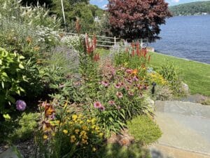 Colorful perennial garden beside a lake with layered plantings and stone edging.