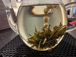 Blooming tea unfurling into flowers inside a glass teapot