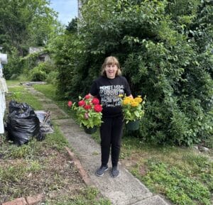 Mimi holding pots of red and yellow zinnias purchased for her foundation garden in Hope, New Jersey.
