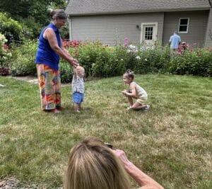 Young girl photographing Thomas in a pollinator garden while her mother photographs the moment.