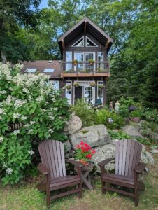 Woodland log home surrounded by lush shade gardens overlooking Highland Lakes.