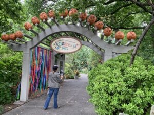 Entrance arch to the Everett Children's Adventure Garden at the New York Botanical Garden, decorated with orange seasonal ornaments and colorful ribbons.