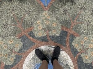 Circular stone mosaic depicting branching trees and floral motifs in the garden pavement.